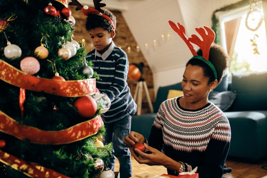 Happy black mother and son enjoying while decorating Christmas t